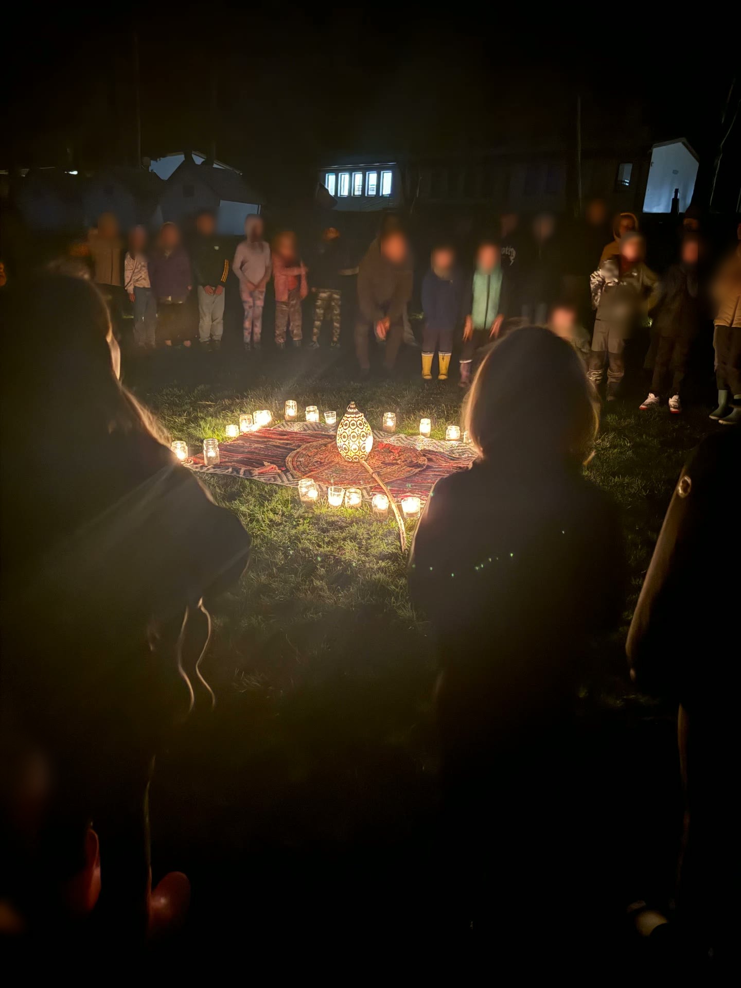 Kruh svíček s lucernou uprostřed na koberci, děti stojí kolem